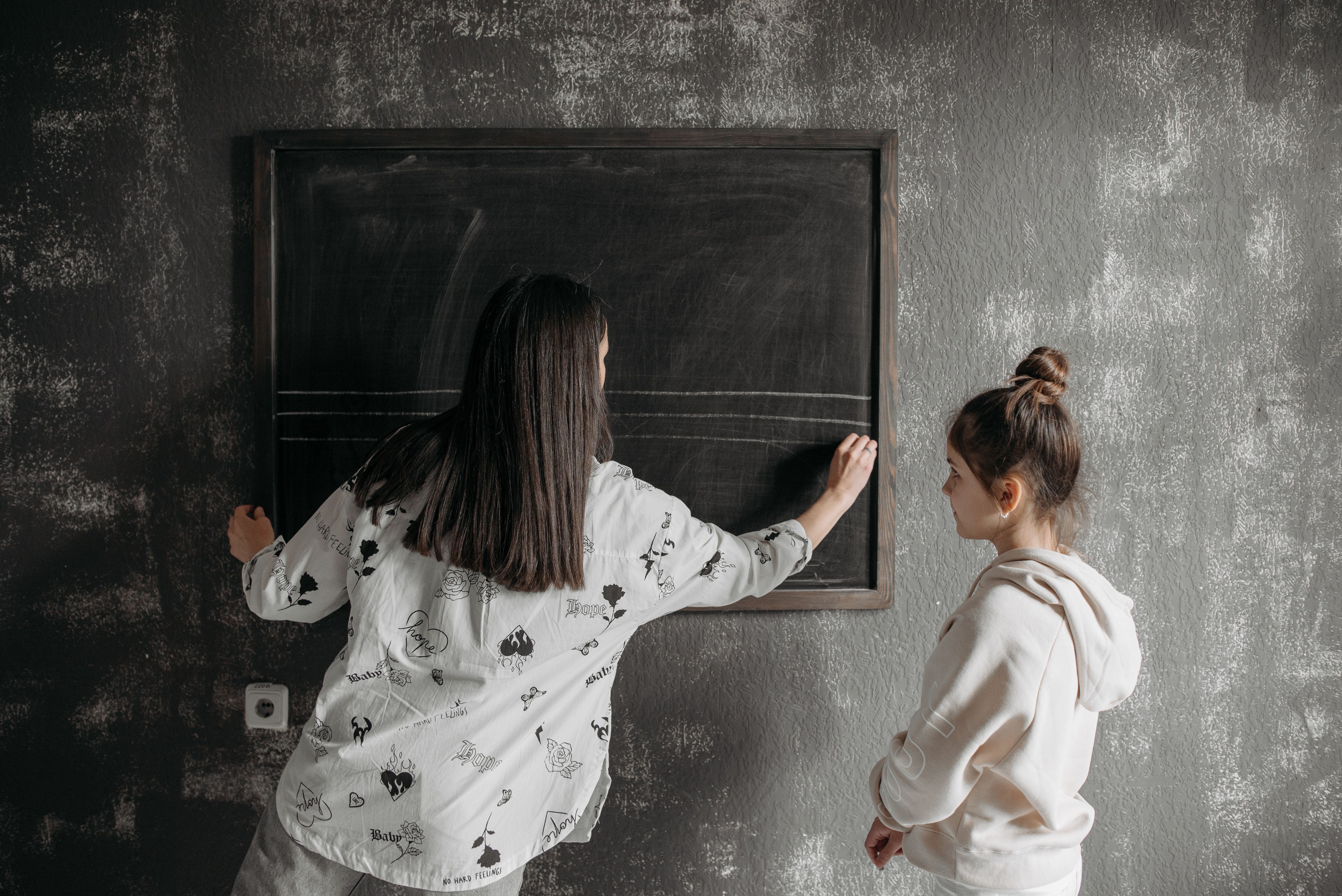Docente y alumna en un espacio de aprendizaje tranquilo frente a un pizarron.