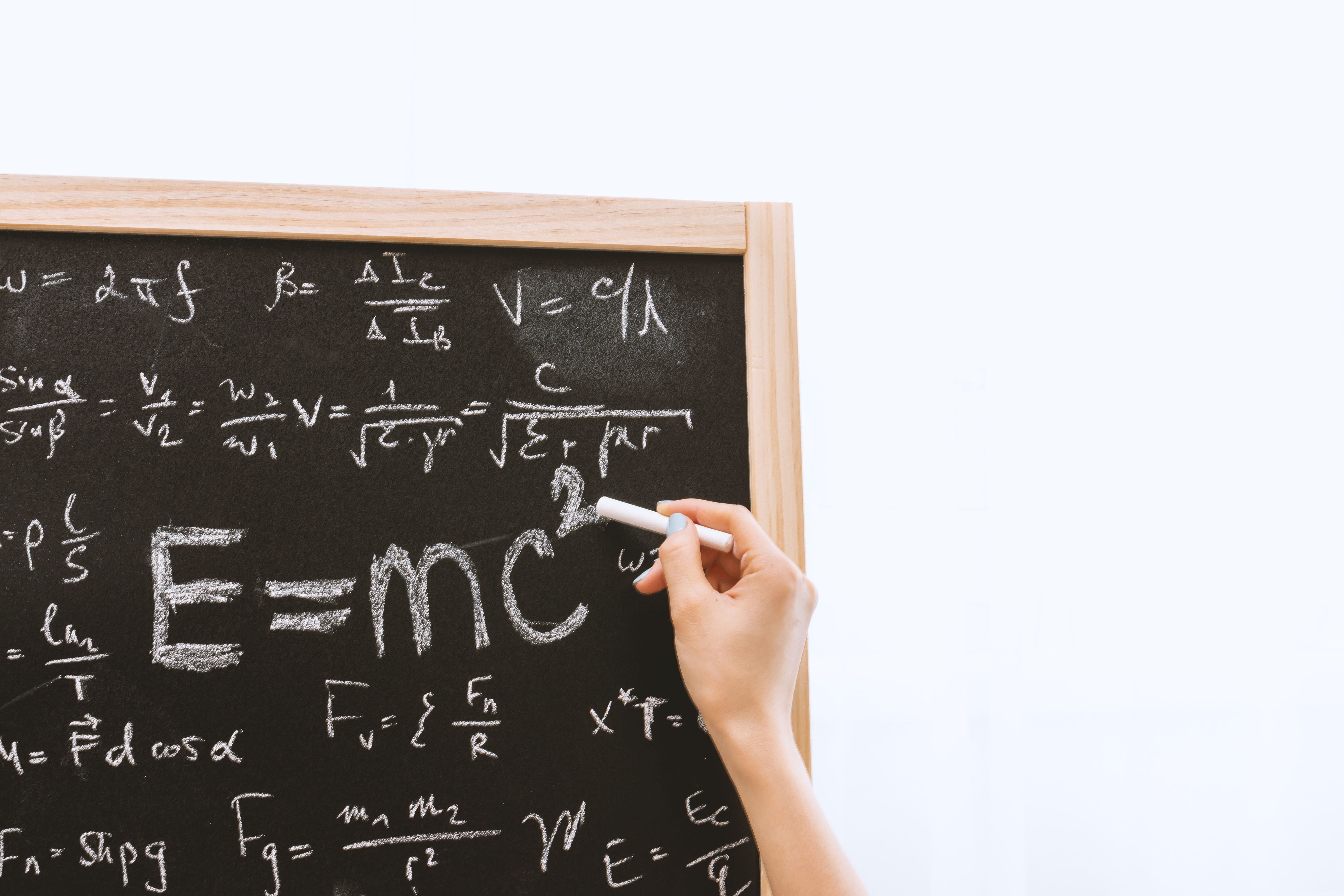 Pizarrón con fórmulas y ecuaciones de física explicadas de forma visual.
